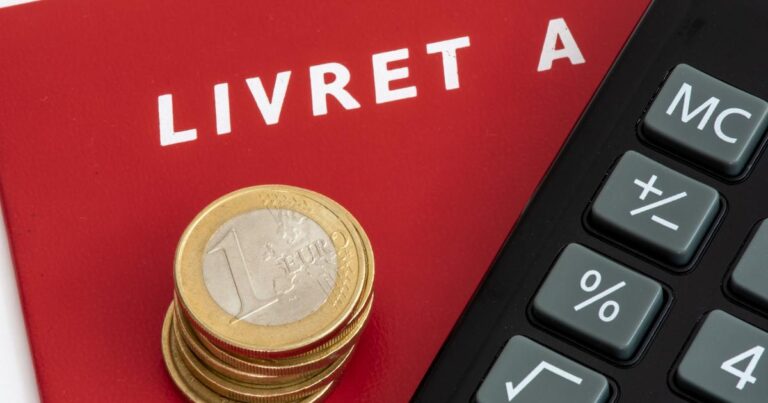 Livret A avec une pile de pièces de monnaie et une calculette.